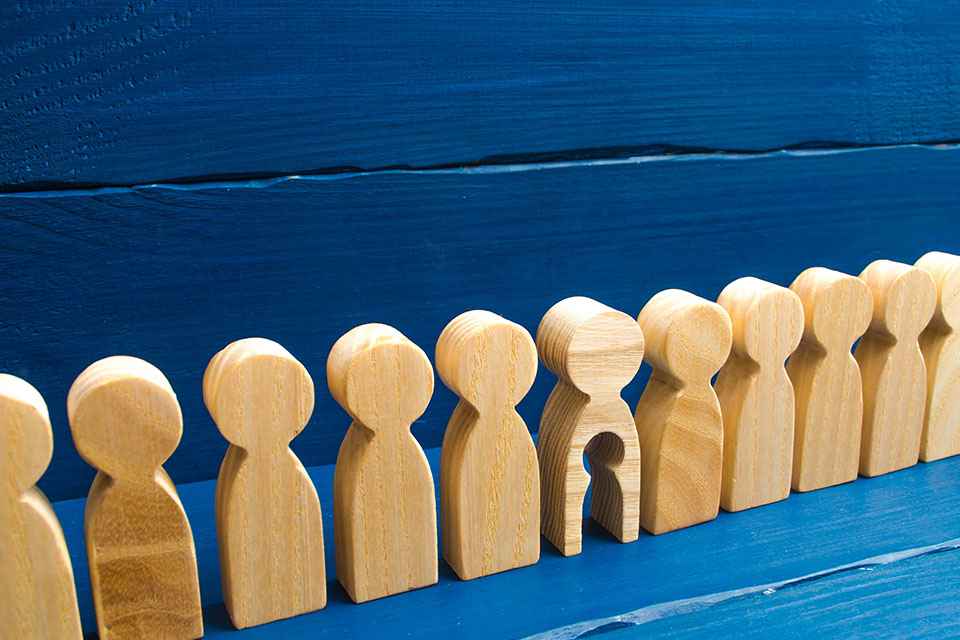 Holzfiguren in einer Reihe, eine hat ein ausgeschnittenes Kind