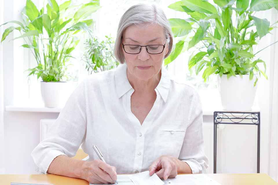 Ältere Dame bearbeitet Unterlagen