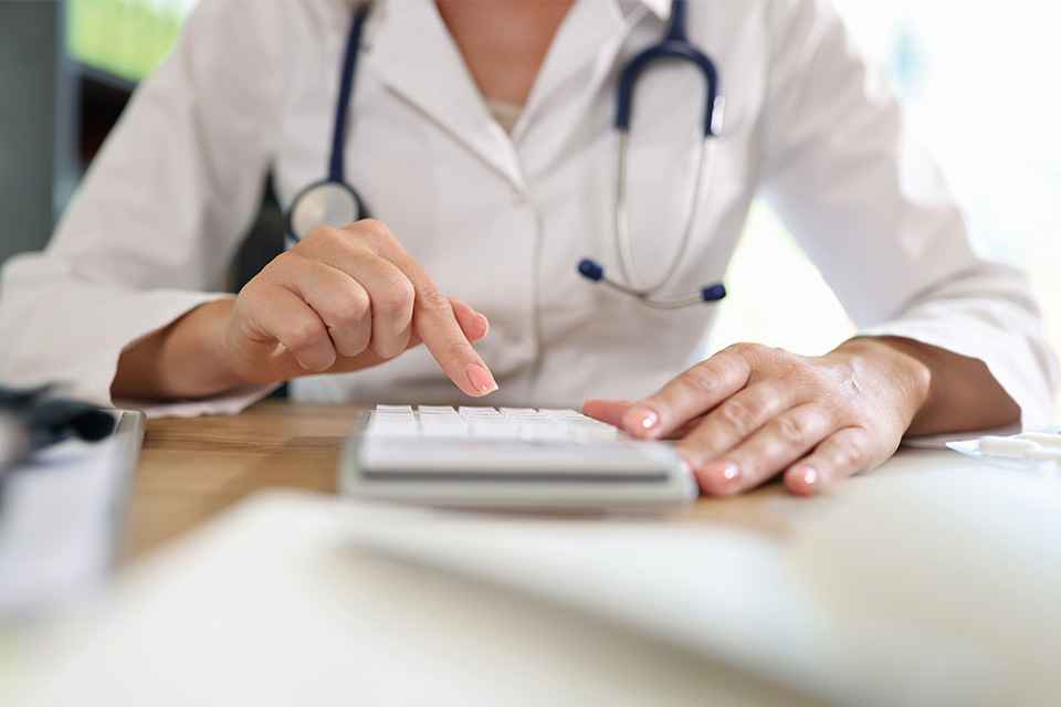 Ärztin arbeitet auf Taschenrechner im Büro