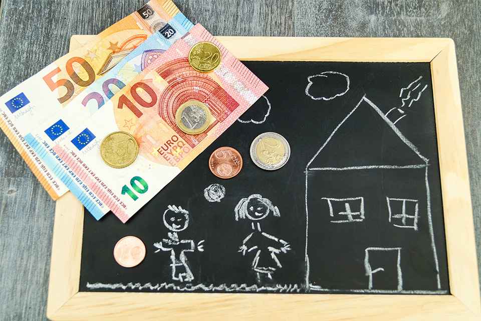 Tafel mit Kinderzeichnung darauf und Bargeld